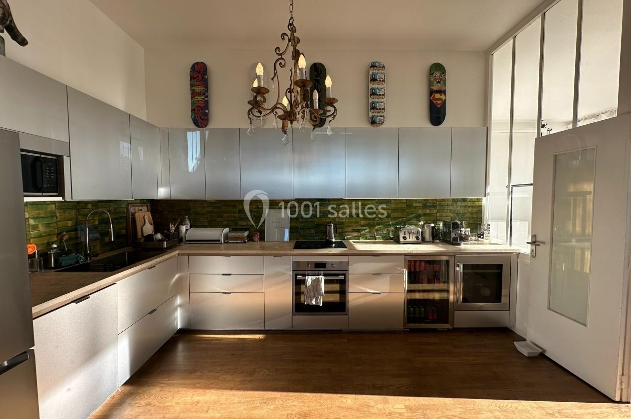 Cuisine moderne avec meubles blancs, plan de travail en bois, crédence verte et décoration murale avec skateboards.