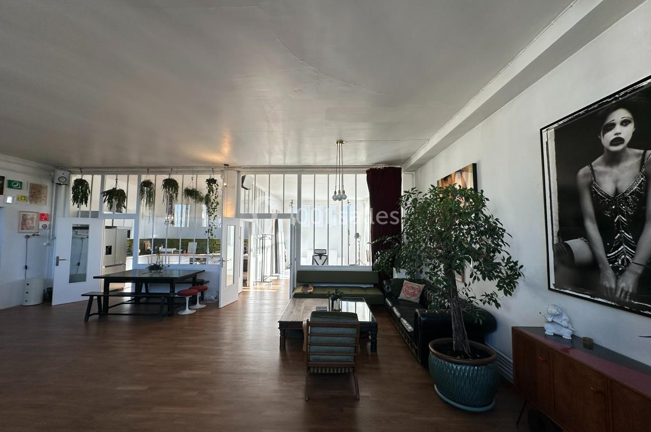 Espace intérieur lumineux avec parquet, mobilier moderne, plantes et grande photo en noir et blanc sur un mur.