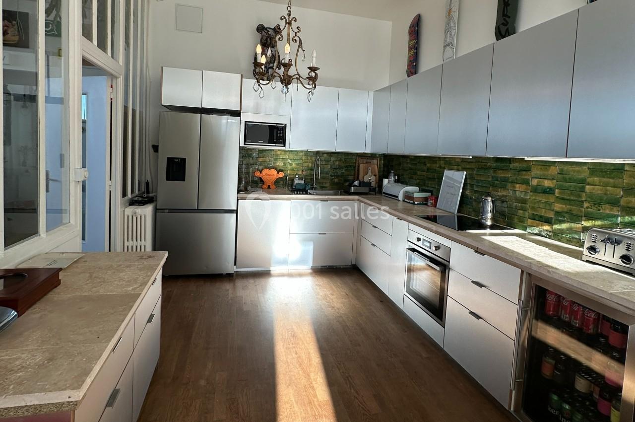 Cuisine moderne avec meubles blancs, plancher en bois, crédence en carreaux verts et électroménagers en acier inoxydable.