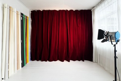 Rideaux rouges fermés dans une pièce lumineuse avec des échantillons de tissus colorés alignés sur la gauche.