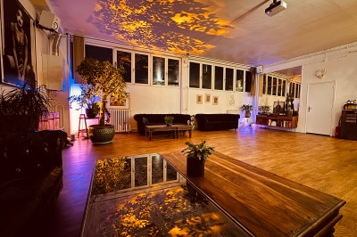 Rideaux rouges fermés éclairés par une lumière rose dans une pièce aux murs blancs avec des voilages translucides.