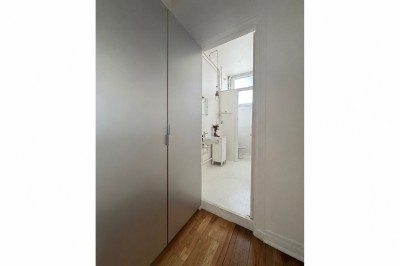 Escalier blanc dans un espace lumineux avec des cadres accrochés aux murs et une fenêtre ouverte.