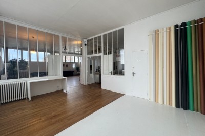 Escalier blanc dans un espace lumineux avec des cadres accrochés aux murs et une fenêtre ouverte.