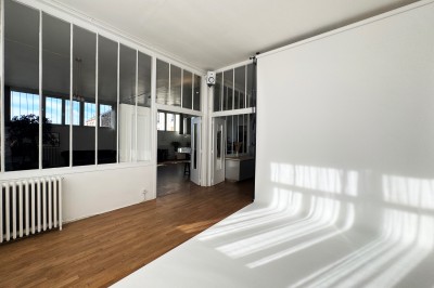 Escalier blanc dans un espace lumineux avec des cadres accrochés aux murs et une fenêtre ouverte.
