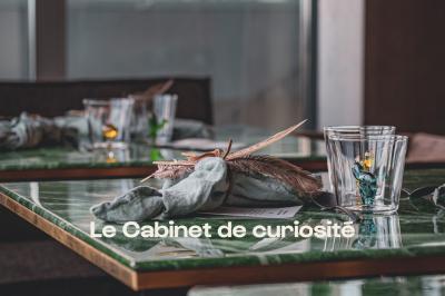 Lustre en cristal suspendu, éclairé, avec un fond sombre et des rideaux texturés.