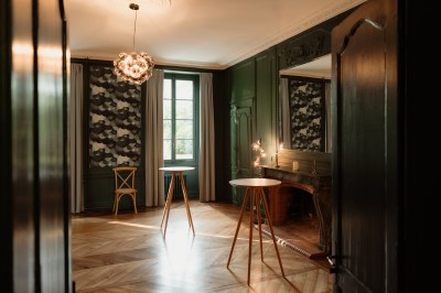 Chambre avec lit double, mur décoré de motifs géométriques bleus et blancs, lumière naturelle entrant par une fenêtre.