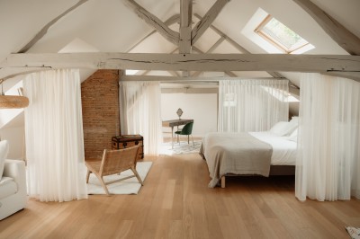 Chambre avec lit double, mur décoré de motifs géométriques bleus et blancs, lumière naturelle entrant par une fenêtre.