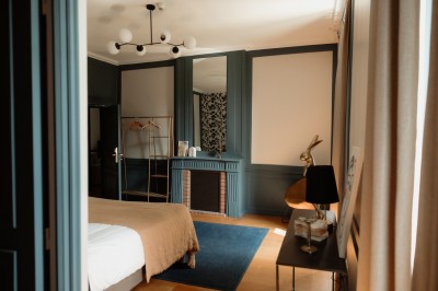 Chambre avec lit double, mur décoré de motifs géométriques bleus et blancs, lumière naturelle entrant par une fenêtre.