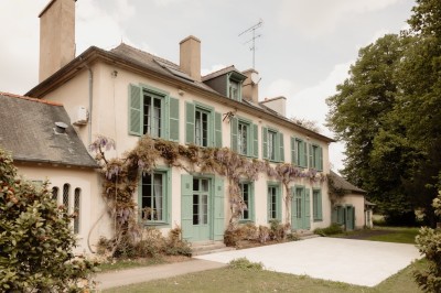Chambre avec lit double, mur décoré de motifs géométriques bleus et blancs, lumière naturelle entrant par une fenêtre.