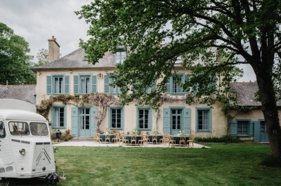 Chambre avec lit double, mur décoré de motifs géométriques bleus et blancs, lumière naturelle entrant par une fenêtre.
