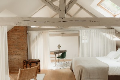 Chambre avec lit double, mur décoré de motifs géométriques bleus et blancs, lumière naturelle entrant par une fenêtre.