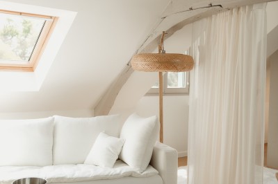 Chambre avec lit double, mur décoré de motifs géométriques bleus et blancs, lumière naturelle entrant par une fenêtre.