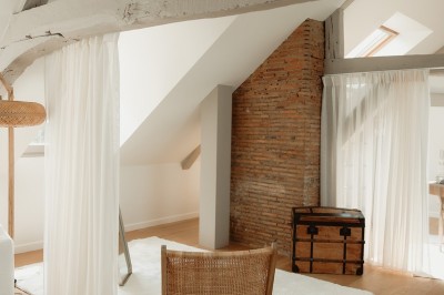 Chambre avec lit double, mur décoré de motifs géométriques bleus et blancs, lumière naturelle entrant par une fenêtre.