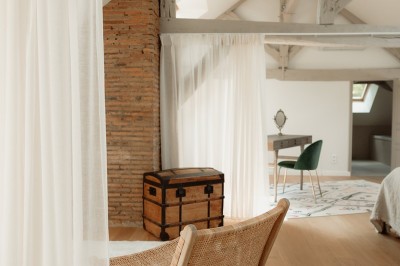 Chambre avec lit double, mur décoré de motifs géométriques bleus et blancs, lumière naturelle entrant par une fenêtre.