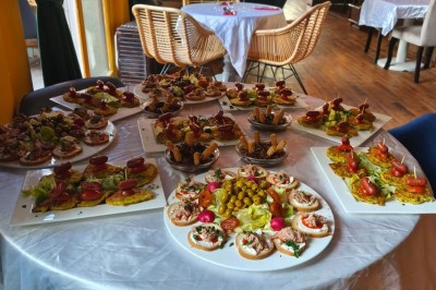 Plateau de canapés variés avec légumes, olives et garnitures, disposé sur une table ronde dans une salle de réception.