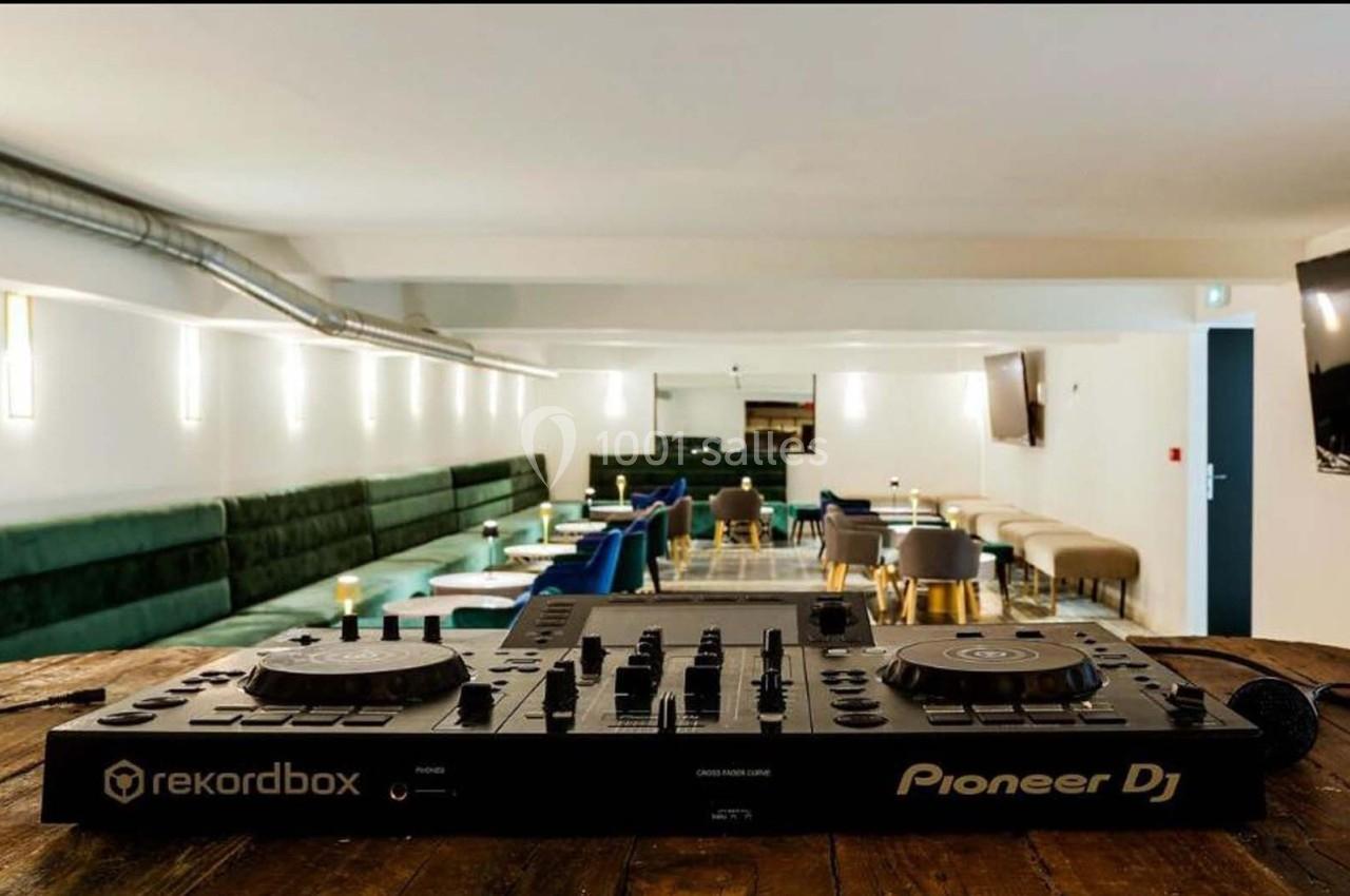 Console de mixage Pioneer DJ posée sur une table en bois, avec un espace lounge moderne en arrière-plan.