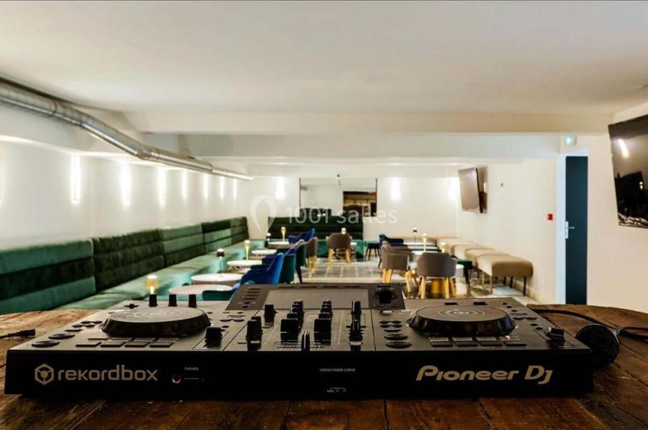 Table de mixage Pioneer DJ sur une table en bois, avec une salle moderne et des sièges en arrière-plan.