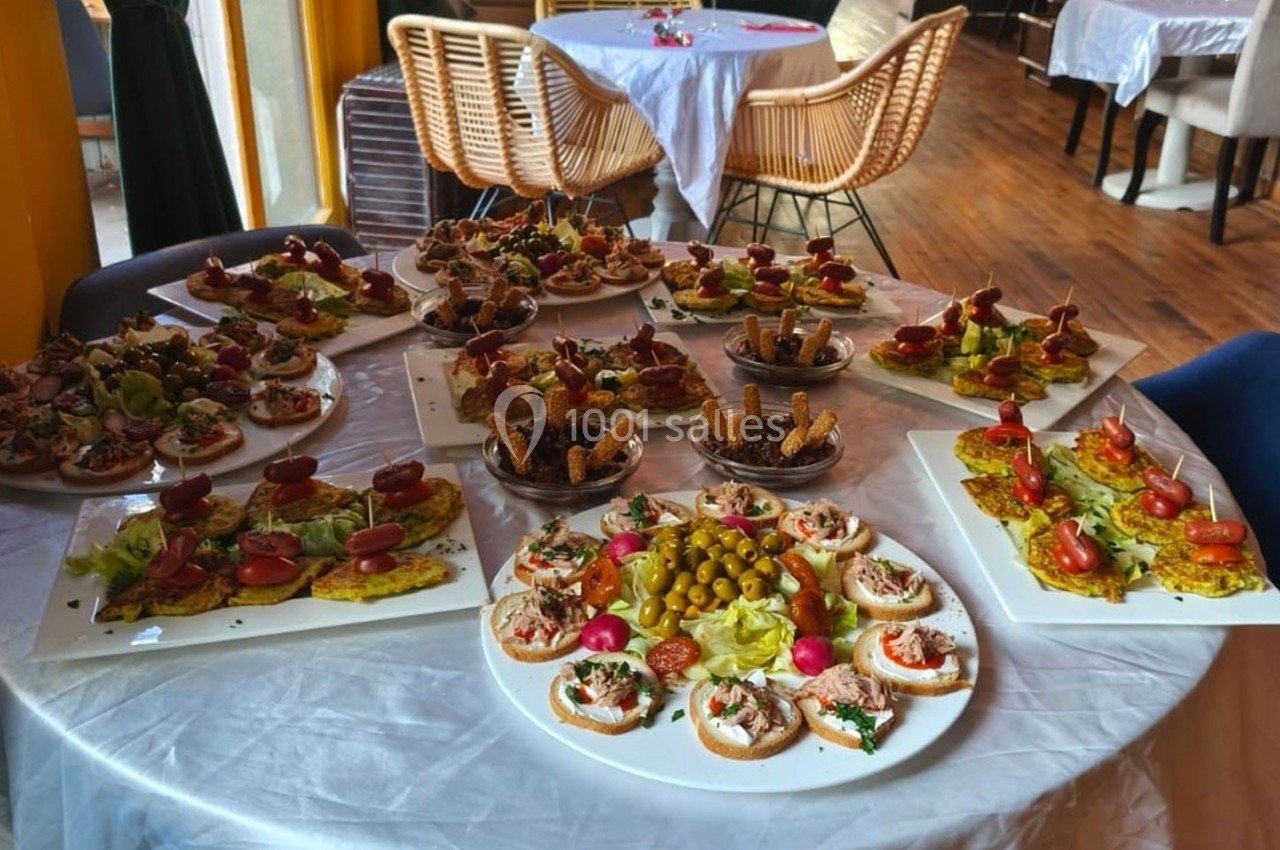 Plateau de canapés variés avec légumes, olives et garnitures, disposé sur une table ronde dans une salle de réception.