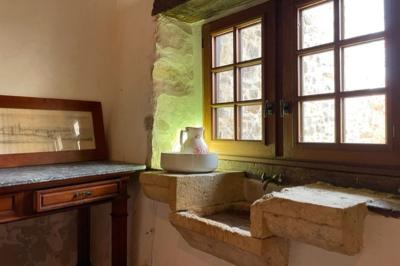 Salle de bain avec deux lavabos sur pied, une douche vitrée et des murs en pierre apparente.