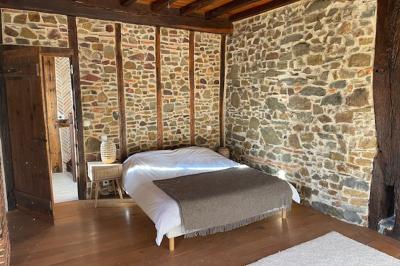 Salle de bain avec deux lavabos sur pied, une douche vitrée et des murs en pierre apparente.