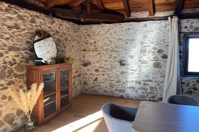 Salle de bain avec deux lavabos sur pied, une douche vitrée et des murs en pierre apparente.