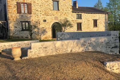 Salle de bain avec deux lavabos sur pied, une douche vitrée et des murs en pierre apparente.