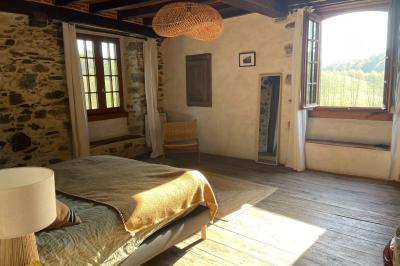 Salle de bain avec deux lavabos sur pied, une douche vitrée et des murs en pierre apparente.