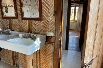Salle de bain avec deux lavabos sur pied, une douche vitrée et des murs en pierre apparente.