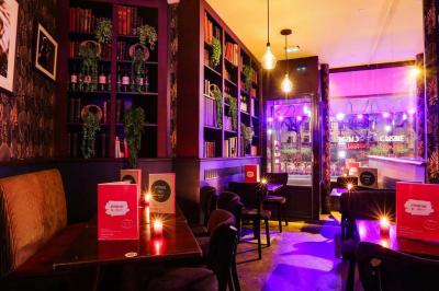 Terrasse d'un café-restaurant éclairée par une lumière violette, avec des tables, menus et bougies allumées.