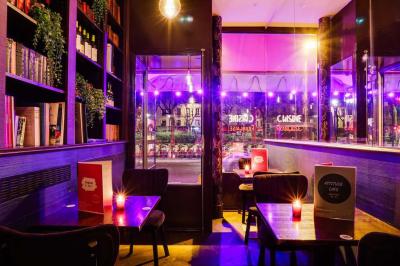 Terrasse d'un café-restaurant éclairée par une lumière violette, avec des tables, menus et bougies allumées.