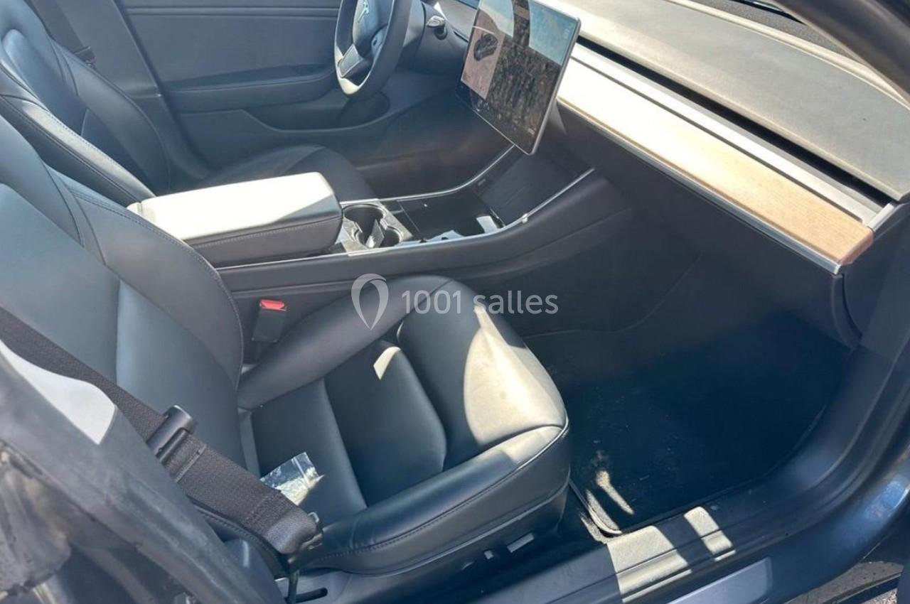 Intérieur d'une voiture avec sièges en cuir noir, écran tactile central et accoudoir avant.