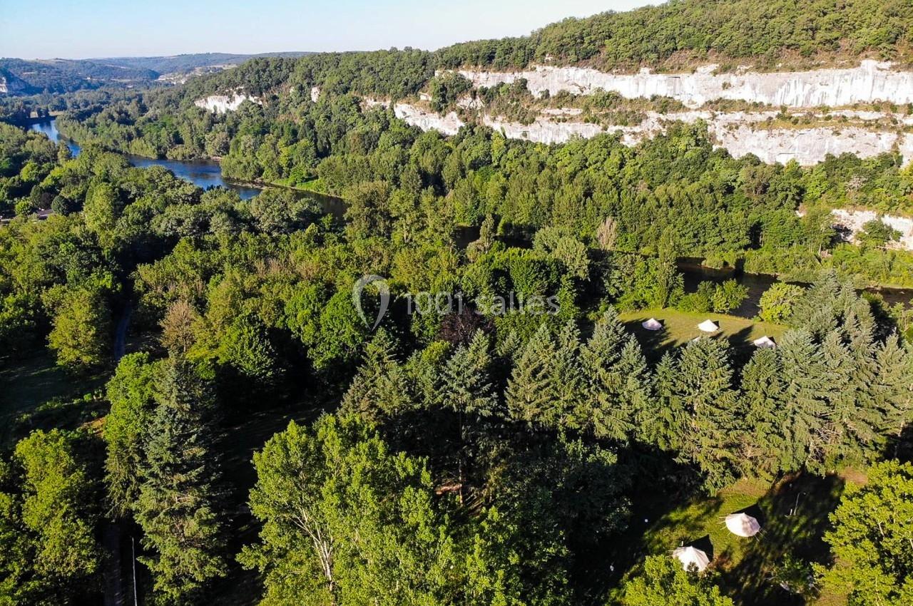 Vue aérienne d'une vallée verdoyante avec une rivière sinueuse, des falaises blanches et une forêt dense.