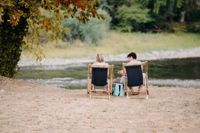Deux personnes pratiquent le yoga en plein air sur des tapis, entourées de végétation.