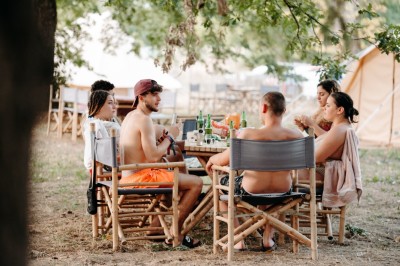 Deux personnes pratiquent le yoga en plein air sur des tapis, entourées de végétation.