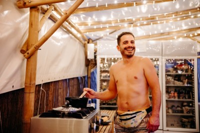 Deux personnes pratiquent le yoga en plein air sur des tapis, entourées de végétation.