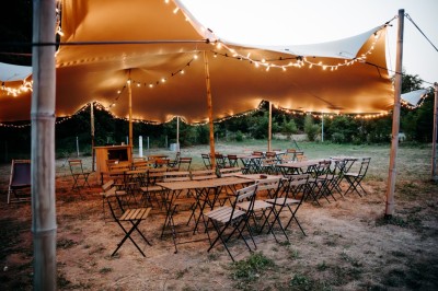 Deux personnes pratiquent le yoga en plein air sur des tapis, entourées de végétation.