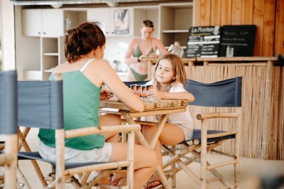 Deux personnes pratiquent le yoga en plein air sur des tapis, entourées de végétation.