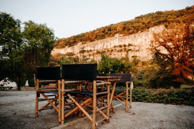 Deux personnes pratiquent le yoga en plein air sur des tapis, entourées de végétation.