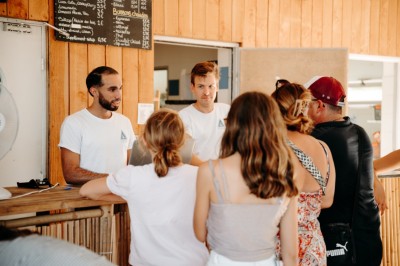 Deux personnes pratiquent le yoga en plein air sur des tapis, entourées de végétation.