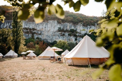 Deux personnes pratiquent le yoga en plein air sur des tapis, entourées de végétation.