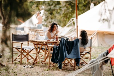 Deux personnes pratiquent le yoga en plein air sur des tapis, entourées de végétation.