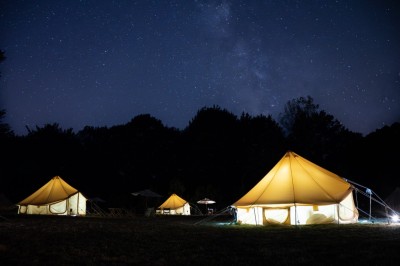 Deux personnes pratiquent le yoga en plein air sur des tapis, entourées de végétation.