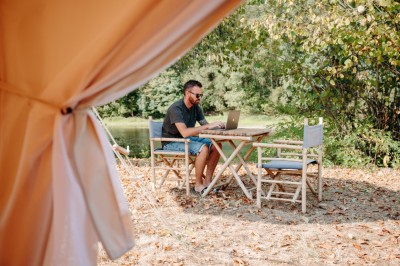 Deux personnes pratiquent le yoga en plein air sur des tapis, entourées de végétation.