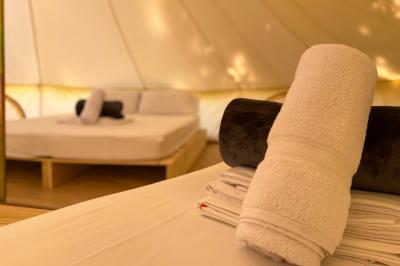 Intérieur d'une tente glamping avec un lit double, des meubles en bois et une ambiance lumineuse et chaleureuse.