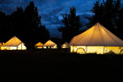 Intérieur d'une tente glamping avec un lit double, des meubles en bois et une ambiance lumineuse et chaleureuse.