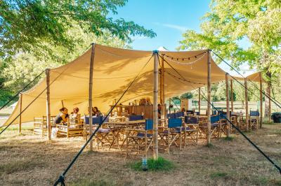 Intérieur d'une tente glamping avec un lit double, des meubles en bois et une ambiance lumineuse et chaleureuse.