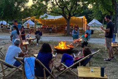 Intérieur d'une tente glamping avec un lit double, des meubles en bois et une ambiance lumineuse et chaleureuse.