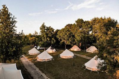 Intérieur d'une tente glamping avec un lit double, des meubles en bois et une ambiance lumineuse et chaleureuse.
