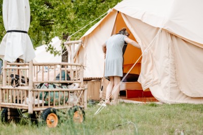 Miniature Location salle Cellettes (Loir-et-Cher) - Lodg’ing Nature Camp Châteaux de la Loire #11 Tentes blanches installées dans un espace naturel près d'une rivière, entourées d'arbres et d'un pont au coucher du soleil.