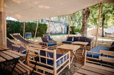 Miniature Location salle Cellettes (Loir-et-Cher) - Lodg’ing Nature Camp Châteaux de la Loire #3 Tentes blanches installées dans un espace naturel près d'une rivière, entourées d'arbres et d'un pont au coucher du soleil.